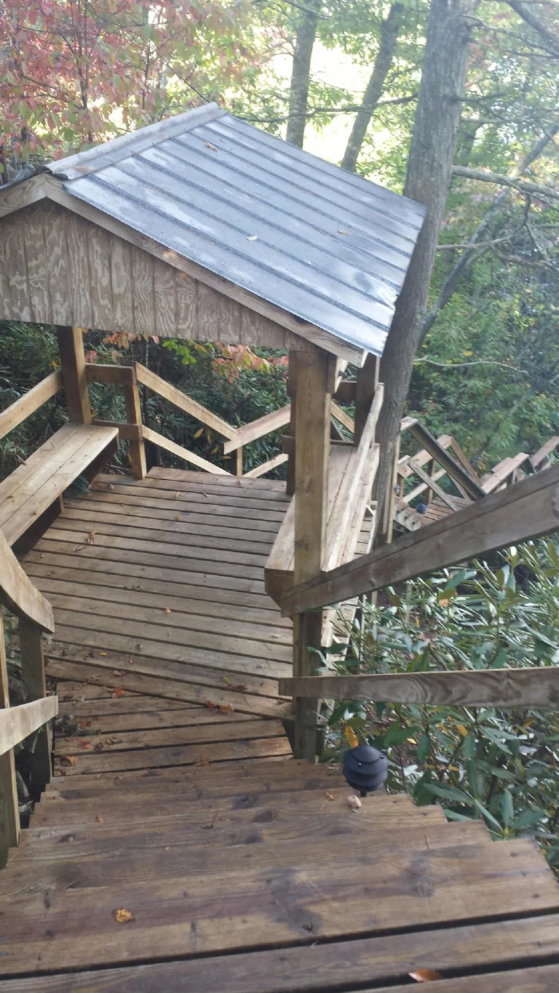 Metal roofed shelter over wooden steps on a wooded walkway — Skylight Repair & Installation work by our crew in Pelham